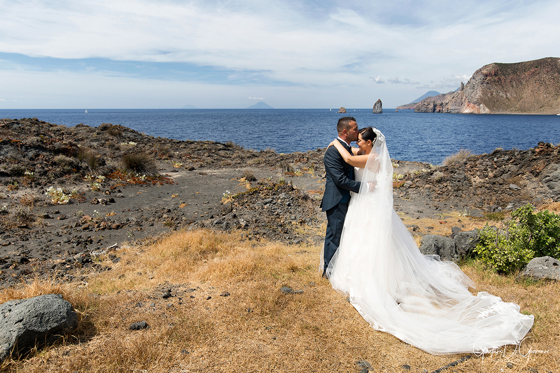 Coppia di sposi con il mare cristallino di Vulcano sullo sfondo, scatto romantico di Gaetano Di Giovanni.